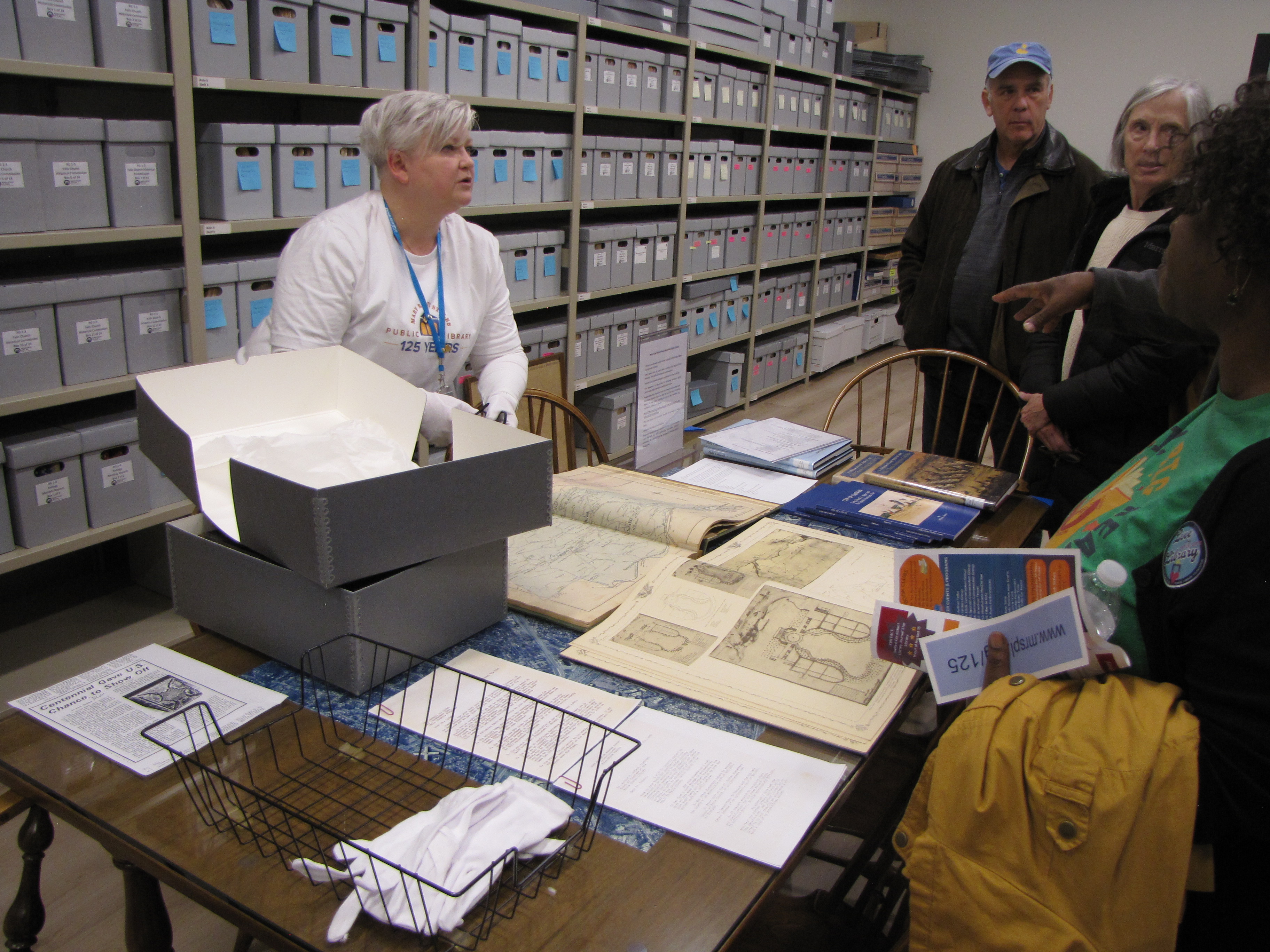 STaff member showing materials to the public in trhe Falls Church History Room duirng the library's 125th Anniversary Kick Off Reception in January 2024 