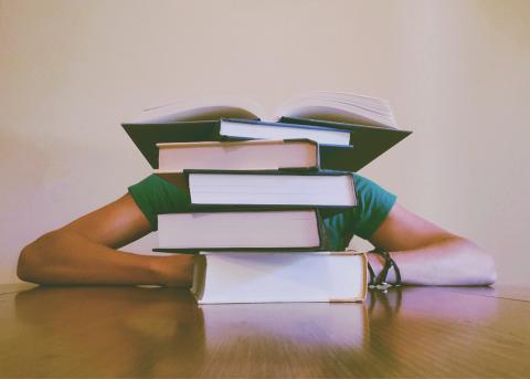 Person reading behind a pile of books